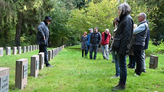 Erwachsene stehen auf einer Kriegsgräberstätte