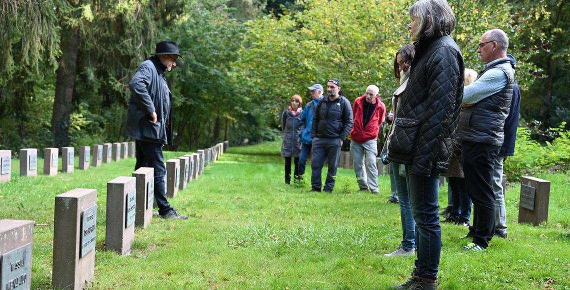 Erwachsene stehen auf einer Kriegsgräberstätte
