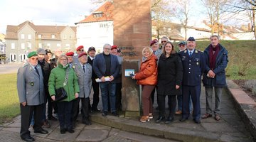 Rund 20 Personen stehen zusammen vor einem Denkmal und schauen in die Kamera