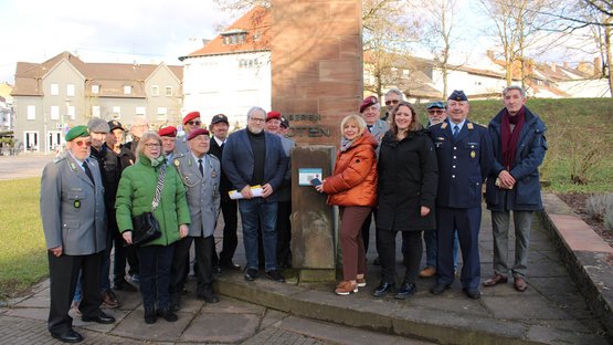 Rund 20 Personen stehen zusammen vor einem Denkmal und schauen in die Kamera