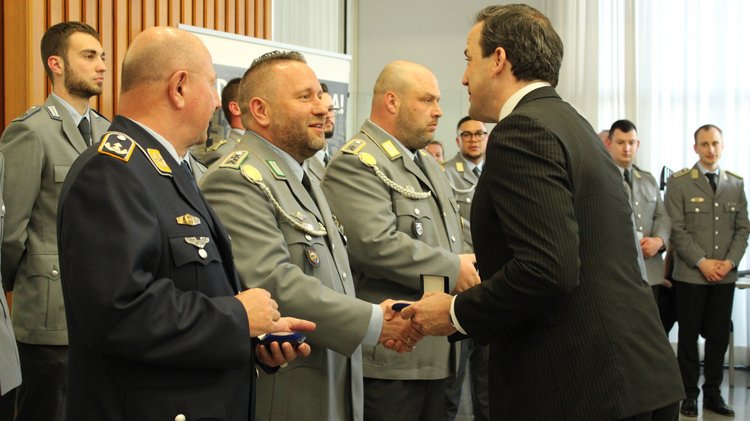 Ein Soldat erhält eine Medaille und schüttelt die Hand eines Herrn im Anzug